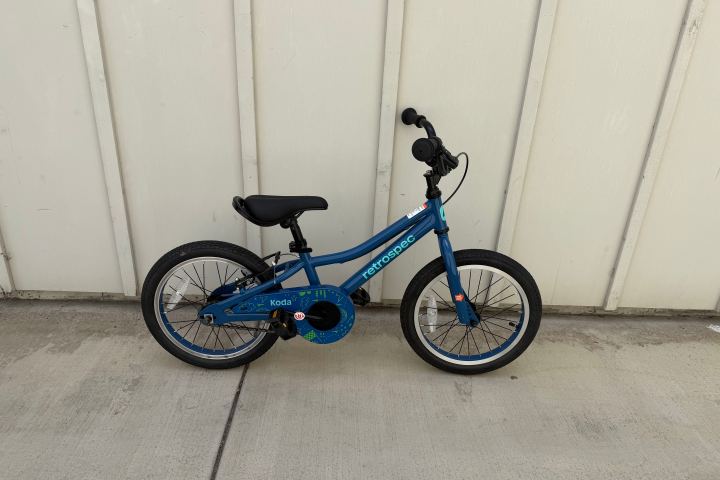 Blue children's bike against a beige wall.