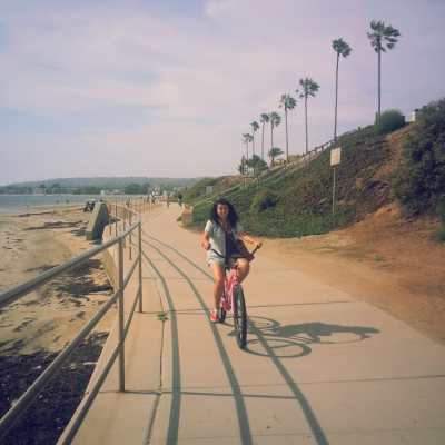 a woman riding a bike down a dirt road